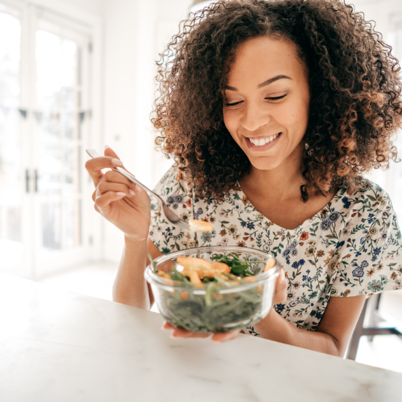 A woman eating a healthy meal up to her kitchen counter.