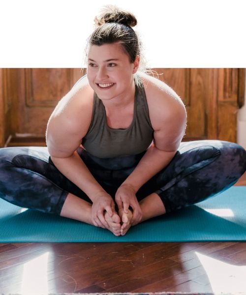 Woman stretching on a mat on the floor and smiling